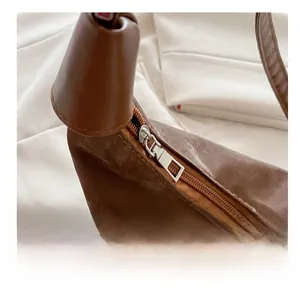 Close-up of smooth silver metal zipper on brown textured faux leather handbag