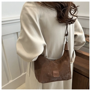 Brown vintage half-moon dumpling bag shown on a model wearing a stylish beige trench coat
