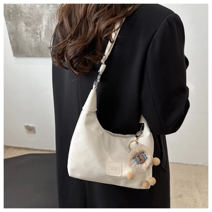 Detail of off-white hobo bag with fashion logo patch and cute plush lion charm on side