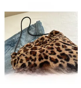 Detail of leopard print faux fur tote bag with slim black shoulder strap on denim