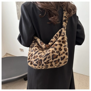 Vue détaillée d'un sac hobo en peluche léopard porté à l'épaule sur un long manteau noir