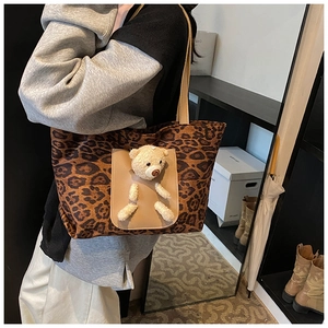 Détail du cabas léopard avec peluche d'ours et poche en cuir porté par un mannequin