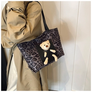 Détail du sac cabas léopard avec un ours en peluche 3D et des anses noires à l'épaule
