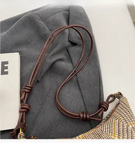 Detail eines handgewebten Lederriemens und Plaid-Tweed-Stoffs an einer Vintage-Tasche