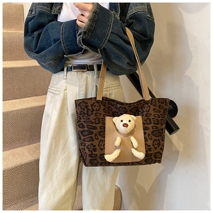 Détail du sac cabas léopard avec poche marron et accessoire ours en peluche mignon décoratif