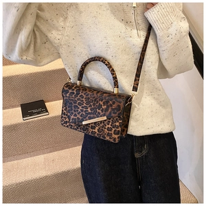 Detail of leopard print crossbody bag featuring gold metal buckle and sturdy top handle