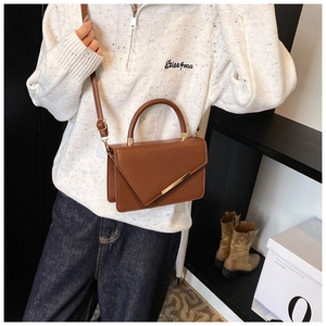 Detailed view of brown leather crossbody bag with metal bar and envelope flap