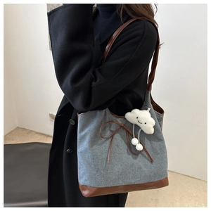 Détail du sac cabas en denim gris avec anses en cuir marron et charme de nuage doux