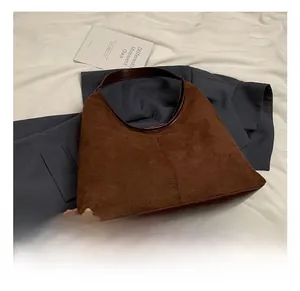 Gedetailleerde close-up van bruine suède tote bag met gladde donkere lederen afwerkingen