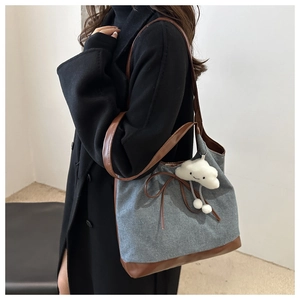 Détail du sac cabas en denim avec finitions en cuir marron et breloque nuage en peluche
