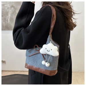 Détail du sac cabas en denim vintage avec bordure en cuir marron et breloque nuage