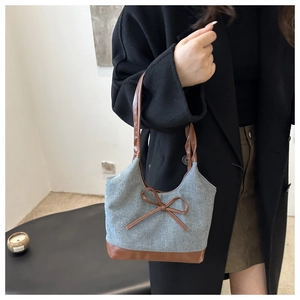 Détail du cabas vintage en toile avec nœud en cuir marron sur un manteau noir