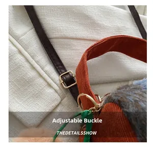 Détail de la boucle dorée sur le sac en velours côtelé orange et peluche bleue