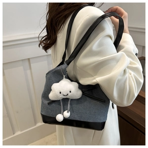 Détail du sac cabas en denim avec finitions en cuir noir et breloque nuage en peluche