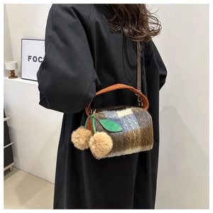 Détail du sac cylindre en laine à carreaux avec texture en fausse fourrure et pompons marrons