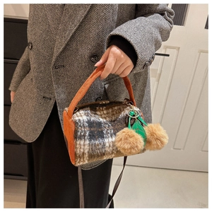 Détail du sac à main à carreaux en laine avec breloque cerise et poignée orange vif