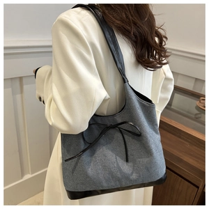 Détail du sac cabas en denim gris avec nœud en cuir noir et fond renforcé