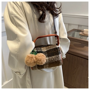 Détail du sac polochon en laine à carreaux avec pendentif cerise et anse orange