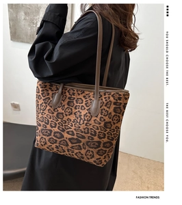 Detail of leopard print tote bag with brown leather straps worn on shoulder