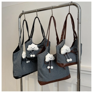 Détail de sacs cabas en toile avec garniture en cuir et breloques nuage sur support métallique
