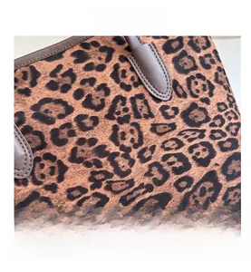 Close-up of leopard print tote bag fabric with dark brown leather trim and neat stitching