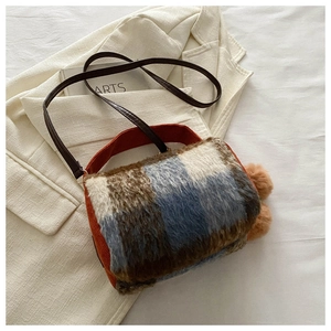 Détail du sac à carreaux en laine avec bordure en velours orange et pompons bruns