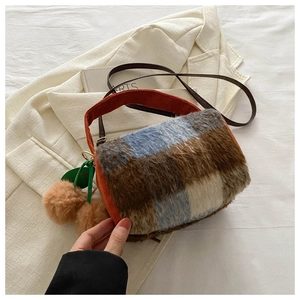 Détail du sac bandoulière en peluche à carreaux avec texture laine et anses oranges
