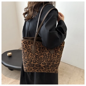 Detailed view of leopard print tote bag with brown leather straps worn on the shoulder
