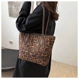 Detailed view of the leopard print tote bag with brown leather trim and shoulder straps
