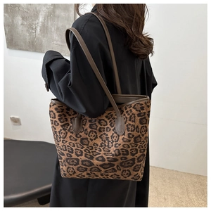 Detailed back view of a large leopard print tote bag with brown leather handles on a model