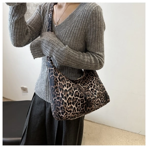 Close-up of leopard print shoulder bag worn by model over a grey knit sweater