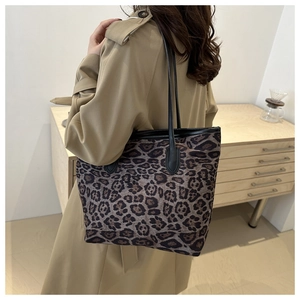 Close-up of leopard print tote bag with black leather handles over a beige trench coat