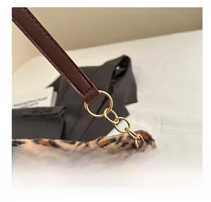 Detail der Plüschtasche mit Leopardenmuster, braunem Lederriemen und Goldbeschlägen