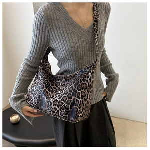 Leopard print crescent hobo bag with adjustable strap worn by model on shoulder