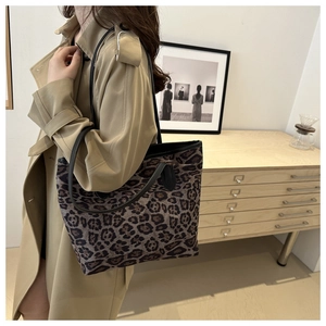 Side view of leopard print tote bag with black handles on a model in minimalist interior