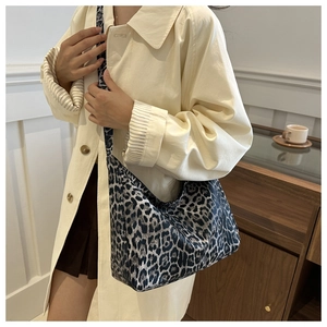 Detailed close-up of a large leopard print hobo shoulder bag worn with a trench coat