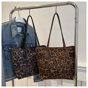 Close-up of leopard print tote bags in cool grey and warm brown tones on a hanger