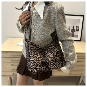 Detail of a leopard print tote bag styled with a tweed blazer for a chic look