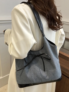 Sac fourre-tout vintage en jean avec nœud en cuir porté par un mannequin pour le style