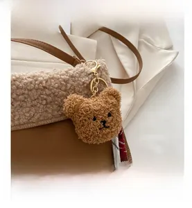 Detail of cute brown plush bear charm with golden clasp and embroidery for handbags