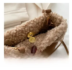 Detail of golden magnetic buckle on brown plush crossbody bucket bag with fuzzy texture