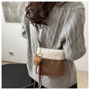 Detail einer braunen Leder-Eimertasche mit weißer Pelzklappe und süßem Bärenanhänger