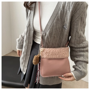 Detail of pink faux shearling bucket bag with plush charm and tassel on model