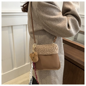 Detail of suede bucket bag with faux shearling flap and cute plush bear charm
