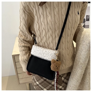 Détail du sac à bandoulière contrasté avec rabat en sherpa blanc et charm ours brun