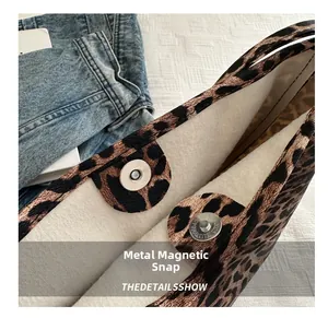 Detail of metal magnetic buckle closure on leopard print tote bag interior