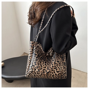 Detail shot of a large leopard print tote bag with leather straps on a model's shoulder