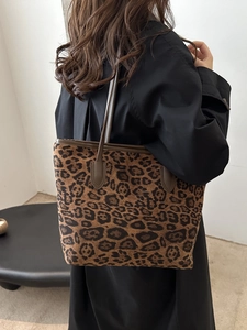 Leopard print tote bag with brown straps worn by a model in a minimalist setting