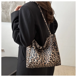 Back view of a large leopard print tote bag with black straps on a female model