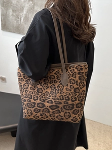 Large leopard print tote bag with leather straps worn by model for fall winter style